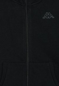 Juodas užtrauktukas džinsinis hoodie, pagamintas iš minkštos medžiagos, su juodu Kappa logotipu ant krūtinės, kengūriškos kišenės ir guma ant rankovių bei apvalkalo.