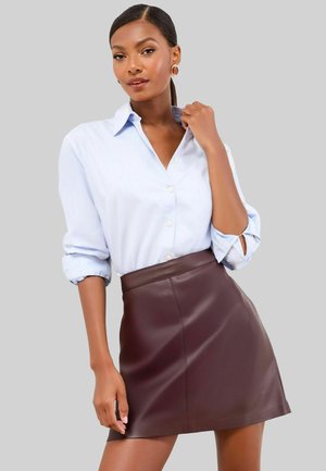 Světle modrá košile s krátkým rukávem, doplněná burgundskou koženou mini sukní. Hladký texture a přiléhavý střih.