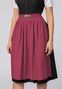 Traditionelles Dirndl-Kleid mit einem schwarzen gemusterten Oberteil und einem plissierten weinroten Rock, akzentuiert mit einem dekorativen Gürtel und floralen Details.