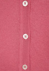 Lyserød strikket cardigan med en central knaplukning med fire runde knapper, ribbet tekstur og glat stof.