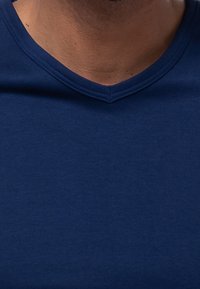 Marineblauwe katoenen T-shirt met een V-hals ontwerp. Zachte textuur met een gladde afwerking en geen zichtbare patronen of hardwaredetails.