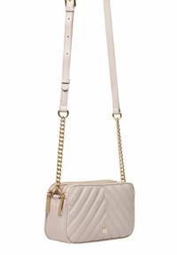 Beżowa torebka pikowana wykonana z syntetycznej skóry, z złotym łańcuchem jako paskiem, podwójnym zamknięciem na zamek i prostokątnym kształtem z wzorem w zygzak.