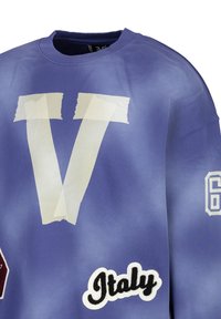 Lila Sweatshirt mit übergroßem, weißem Tape-Streifen-„V“-Grafik, besticktem „Italien“ und der Nummer „67“. Weicher Stoff mit entspannter Passform.