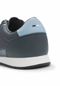 Miestenské tenisky s textúrovaným tmavosivým sieťovaným zvrškom, svetlomodrou pätou a bielou podrážkou s vzorom rybej kosti. Doplňujúce detaily v čiernej, bielej a béžovej farbe.