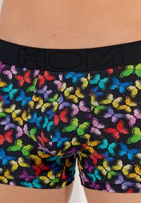 Boxer shorts med svart bakgrund, prydda med ett färgglatt fjärils mönster i olika nyanser. Elastisk midja med varumärket "HOM."