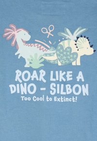 Dos dinosaurios de dibujos animados con plantas y tijeras encima, con el texto "Roar like a Dino - Silbon Too Cool to Extinct!" en tela azul.
