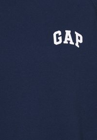 Sweatshirt en coton bleu marine avec un logo "GAP" blanc en lettres arquées. Texture douce avec un col rond côtelé.