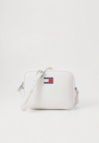 Weiße Umhängetasche aus synthetischem Material mit verstellbarem Riemen. Verfügt über eine rechteckige Form und ein Logo mit roten und blauen Akzenten auf der Vorderseite.