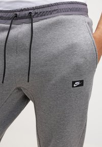 Gray sweatpants with an elastic waistband, drawstring closure, and black Nike logo patch. Soft texture and straight fit design.