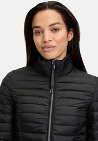 Sort quiltet jakke med høj krave, der har lynlåslukning og tekstureret stof. Slim fit med horisontale sømdetaljer.