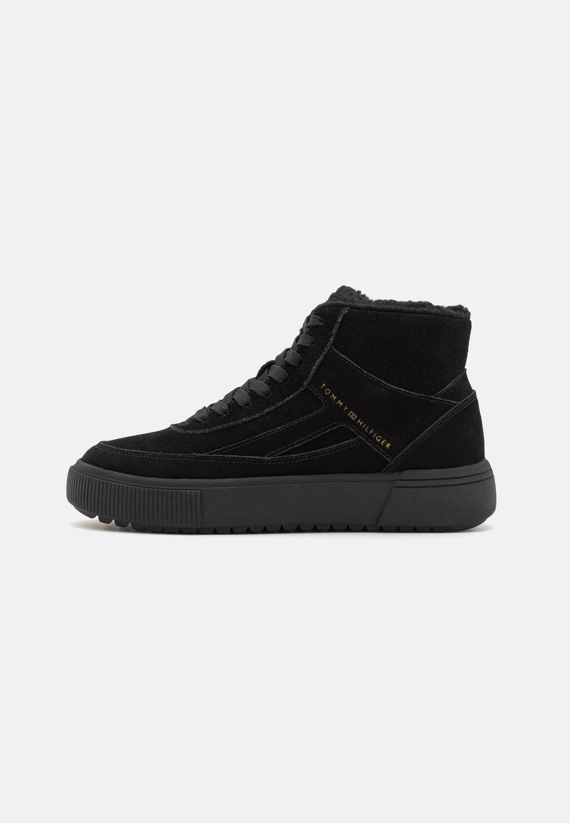 Czarne wysokie sneakersy z zamszu z teksturowaną podeszwą, posiadające sznurowadła i złote logo marki z boku.