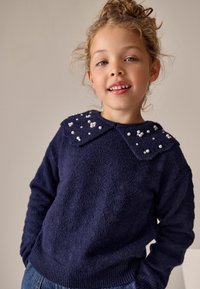 Dunkelblauer Pullover aus strukturiertem Stoff, mit einem großen Kragen, der mit weißen Perlen verziert ist, und einer lässigen Passform mit gerippten Bündchen und Saum.