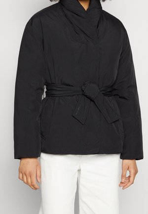 Doudoune noire avec un design enveloppant, présentant une taille ceinturée, un col montant et une texture lisse. Des coutures horizontales sont visibles.