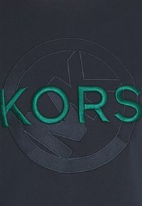 Felpa navy con logo "KORS" ricamato di colore verde scuro, accompagnato da un emblematico cerchio sullo sfondo, che mette in mostra una finitura texturizzata.