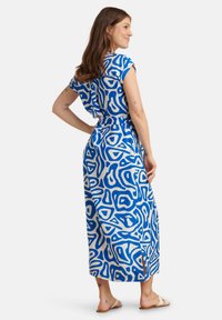 Maxikleid in Blau und Creme mit abstrakten Mustern, kurzen Ärmeln und Taillenknoten. Verfügt über seitliche Schlitze für mehr Bewegungsfreiheit.