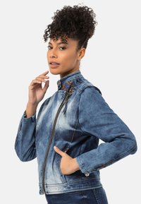Jeansjacke mit einem Ombre-Blauwasch, Reißverschluss, hohem Kragen und filigranem Musterakzent an den Schultern. Mit Seitentaschen.