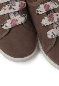 Sneakers in tela marrone con suole in gomma bianche, caratterizzati da lacci con un motivo floreale che aggiungono un tocco decorativo. Texture complessiva liscia.