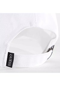 Casquette blanche avec une texture nervurée, une sangle ajustable et une étiquette en tissu noir avec le nom de la marque positionnée près de l'arrière.