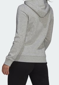 Světle šedá mikina s kapucí, vyrobená z měkkého materiálu, s šňůrkovou kapucí, žebrovanými manžetami a spodním lemováním. Design je jednoduchý, bez viditelných vzorů.