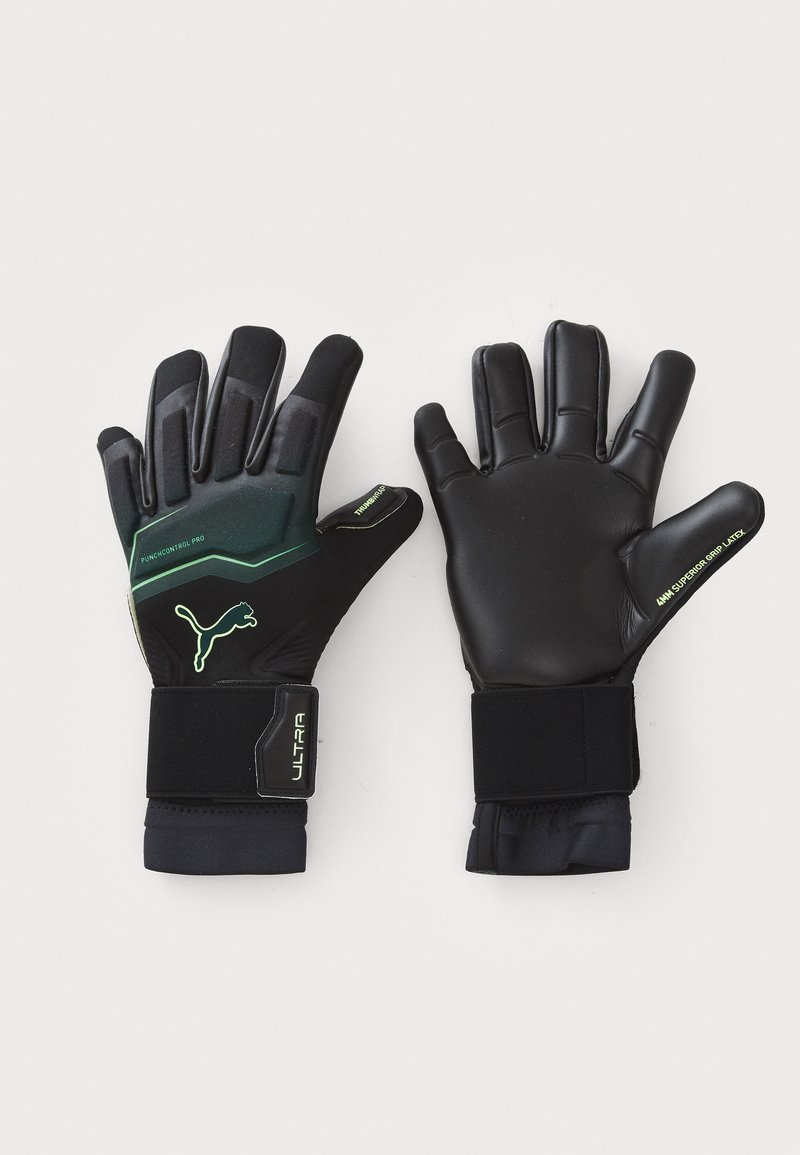Svarta målvaktshandskar med texturerade gummiknoppar på fingertopparna och handledsremmar. Utrustade med gröna accenter och logotyp. Tillverkade av latex och syntetiska material.