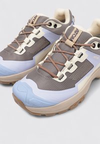 Baskets de sport grises et bleues avec un design texturé, comportant des accents beiges, des lacets marron et une semelle en caoutchouc durable.