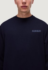 Felpa di cotone blu navy con collo rotondo, caratterizzata da un piccolo logo bianco sul petto. Texture liscia e vestibilità classica.