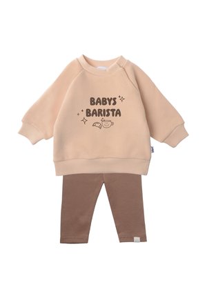 Peach sweatshirt with "BABY'S BARISTA" text, paired with brown ribbed leggings. Soft fabric, long sleeves, and cuffed hems enhance comfort.