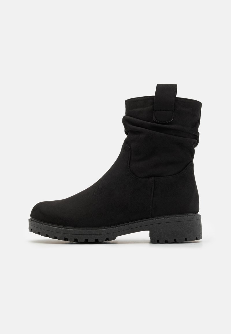Bottines noires en matériau doux avec un design flou, bout rond et semelle en caoutchouc solide avec un motif texturé.