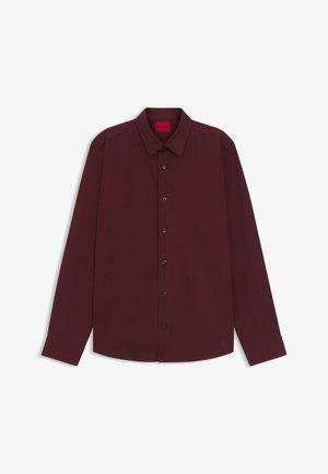 Long-sleeve burgundy shirt made of smooth fabric, featuring a classic collar, black button closures, and stitched logo detail on the hem.