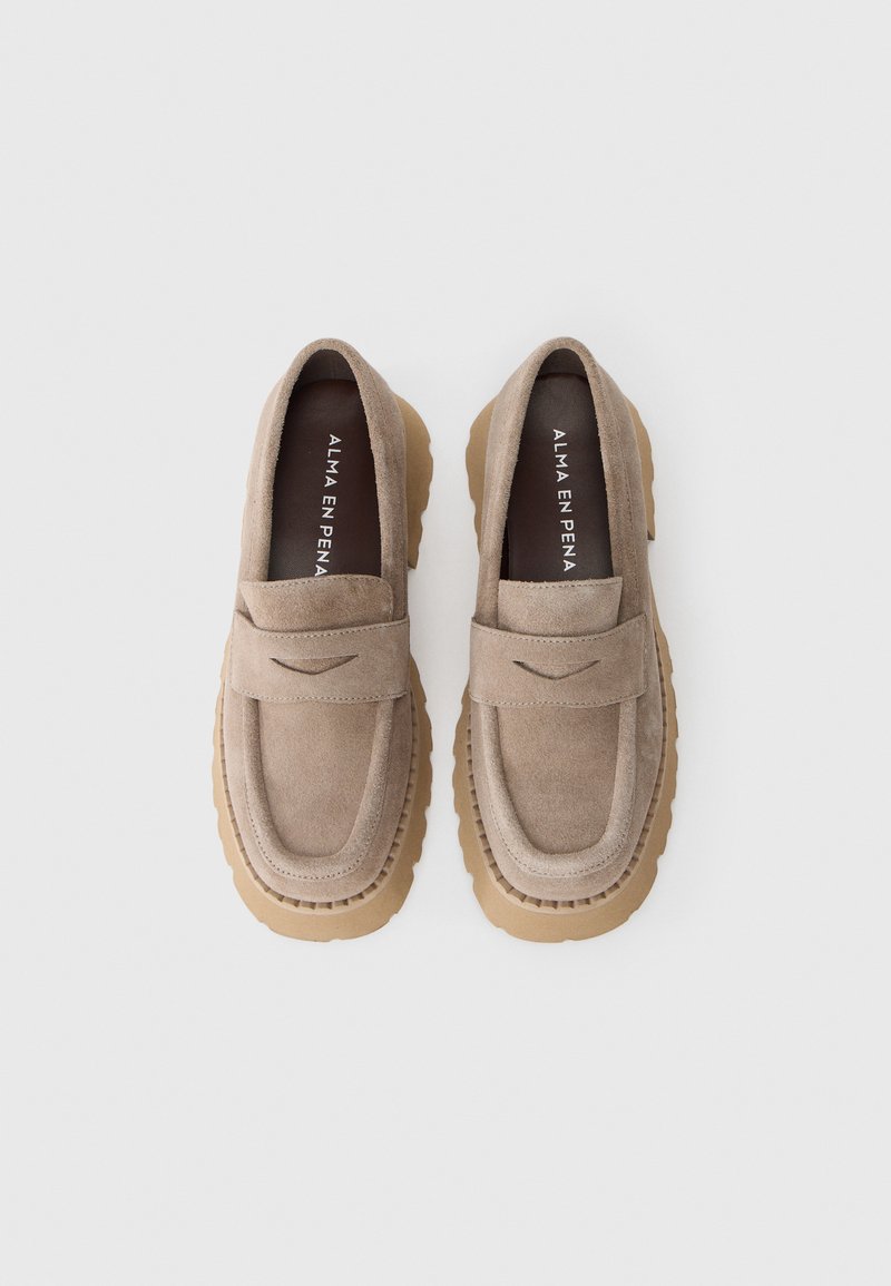 Beige Wildleder Slipper mit gepolstertem Blatt, runder Zehenpartie und dicker Sohle aus Gummi mit gerippten Details am Rand.