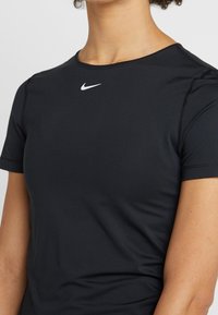 Persona lleva una camiseta atlética negra ajustada de manga corta de Nike con el logotipo en forma de swoosh blanco en el pecho.