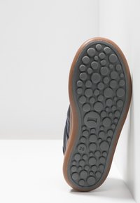La suola della scarpa presenta una superficie in gomma grigia con cerchi texture e un bordo marrone. L'etichetta della taglia 28 è visibile vicino al tallone.