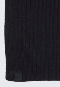 Pull en tricot de couleur noire unie avec une texture côtelée. Présente une petite étiquette noire au bas avec un logo. Design simple et allongé.