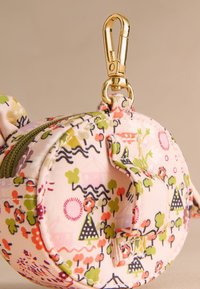 Kerek textil tasak virág- és tájmintával rózsaszín, zöld és fekete színekben. Arany forgókapoccsal és zöld cipzárral rendelkezik.