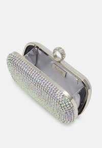 Srebrna kopertówka z metalicznym wykończeniem, ozdobiona opalizującymi kryształkami. Posiada okrągłe, zdobione zamknięcie na górze oraz satynową podszewkę.