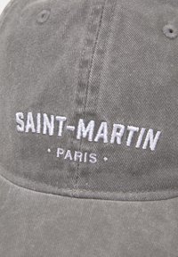Casquette en coton gris avec le texte brodé en blanc "SAINT-MARTIN PARIS." Forme structurée avec un bord courbé et un tissu texturé.