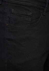 Svarta jeans i denim med en mjuk textur, standard femfickorsdesign och subtila sömdetaljer längs sömmarna och fickorna.