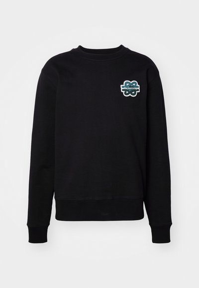 Must käsivarrega must sweatshirta, millel on ümar kaelus ja tekstuuriga tikandiga roheline ja valge logo rinnal. Pehme kangas.