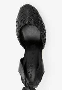 Chaussure à bride arrière en cuir tressé noir avec un bout arrondi, tige texturée et une semelle intérieure noire lisse embossée de "NEXT FOREVER COMFORT."