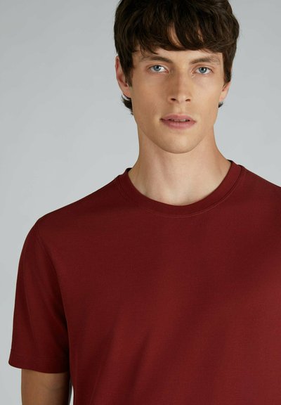 T-shirt in cotone borgogna con scollo rotondo e maniche corte, caratterizzato da una texture liscia e dettagli di cucitura minimi.
