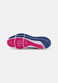 Semelle d’une chaussure de running avec une bande de roulement en caoutchouc rose, bleu marine et blanc, conçue pour l’adhérence et la flexibilité.
