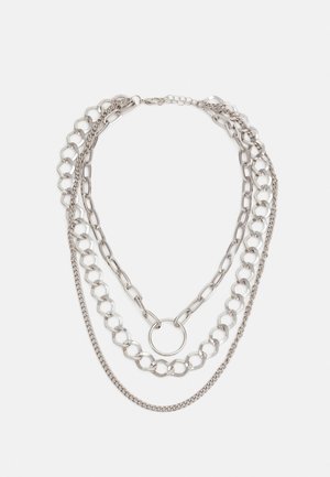 Collier composé de chaînes en argent superposées avec trois styles de chaînes distincts, incluant un détail central en forme d'anneau et une fermeture à boucle de homard.