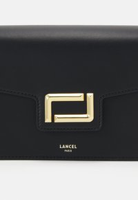 Μαύρο δερμάτινο πορτοφόλι με λεία υφή, διαθέτοντας χρυσό γεωμετρικό κούμπωμα και ανάγλυφο λογότυπο "LANCEL PARIS" σε χρυσό.