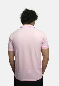 Polo shirt rosa con colletto, caratterizzato da bordi blu e arancioni in contrasto sul colletto e sulle maniche. Realizzato in morbido tessuto di cotone.