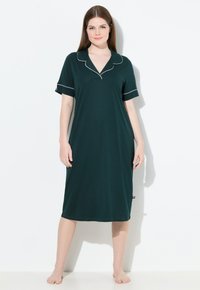 Vestito da notte verde scuro fino al ginocchio in morbido cotone, con scollatura a V profonda, maniche corte e piping bianco lungo il colletto e i bordi delle maniche.