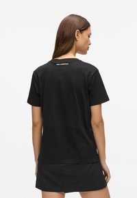 Must musta T-särk lühikeste varrukatega, ümarate kaelustega ja tagaküljel "KARL LAGERFELD" logo, sile tekstuur.