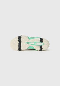 Sole di scarpa sportiva nera con motivo testurizzato; presenta un accento verde menta e sezioni in gomma bianca. Elementi di trazione neri molto evidenti.