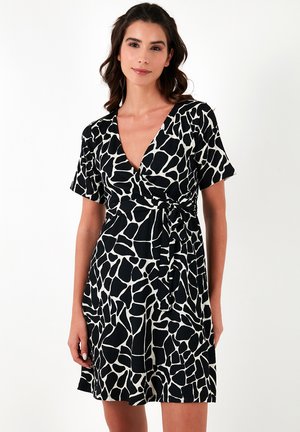 Black and white wrap dress featuring a v-neck, short sleeves, and a giraffe print design. The fabric has a textured appearance with a tie waist.