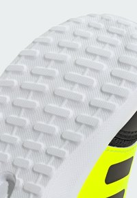 Shoe sole featuring a textured white rubber with a hexagonal grip pattern, complemented by a bright yellow and black upper.