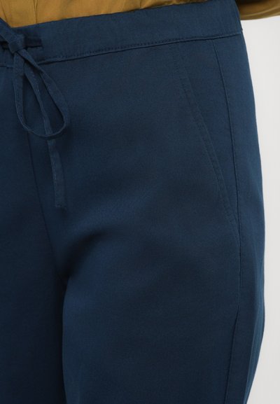 Mornarsko modre hlače z gladko teksturo, ki imajo elastični pas z vrvico in stranske žepke.